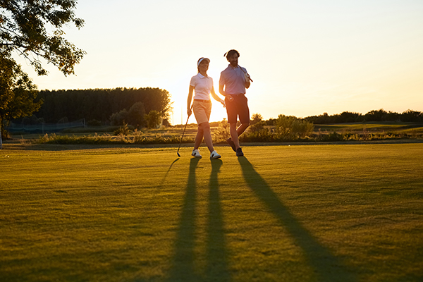 Lachende Golfer bei Sonnenuntergang auf dem Platz